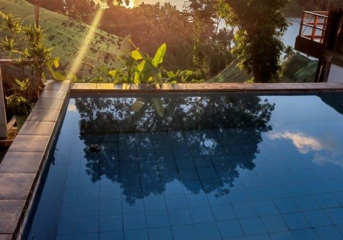 A swimming pool with a view of a river and trees