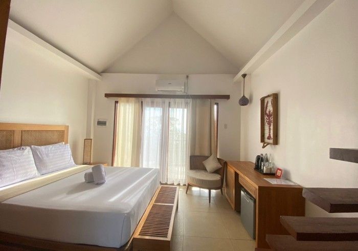 A hotel room with a king size bed and a chair