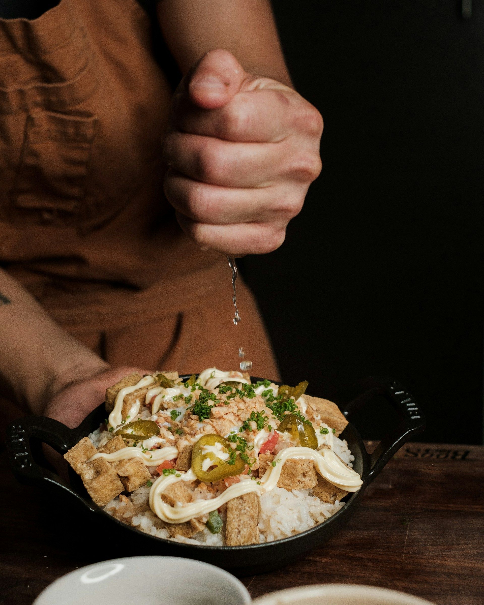 A person is sprinkling salt on a bowl of food.