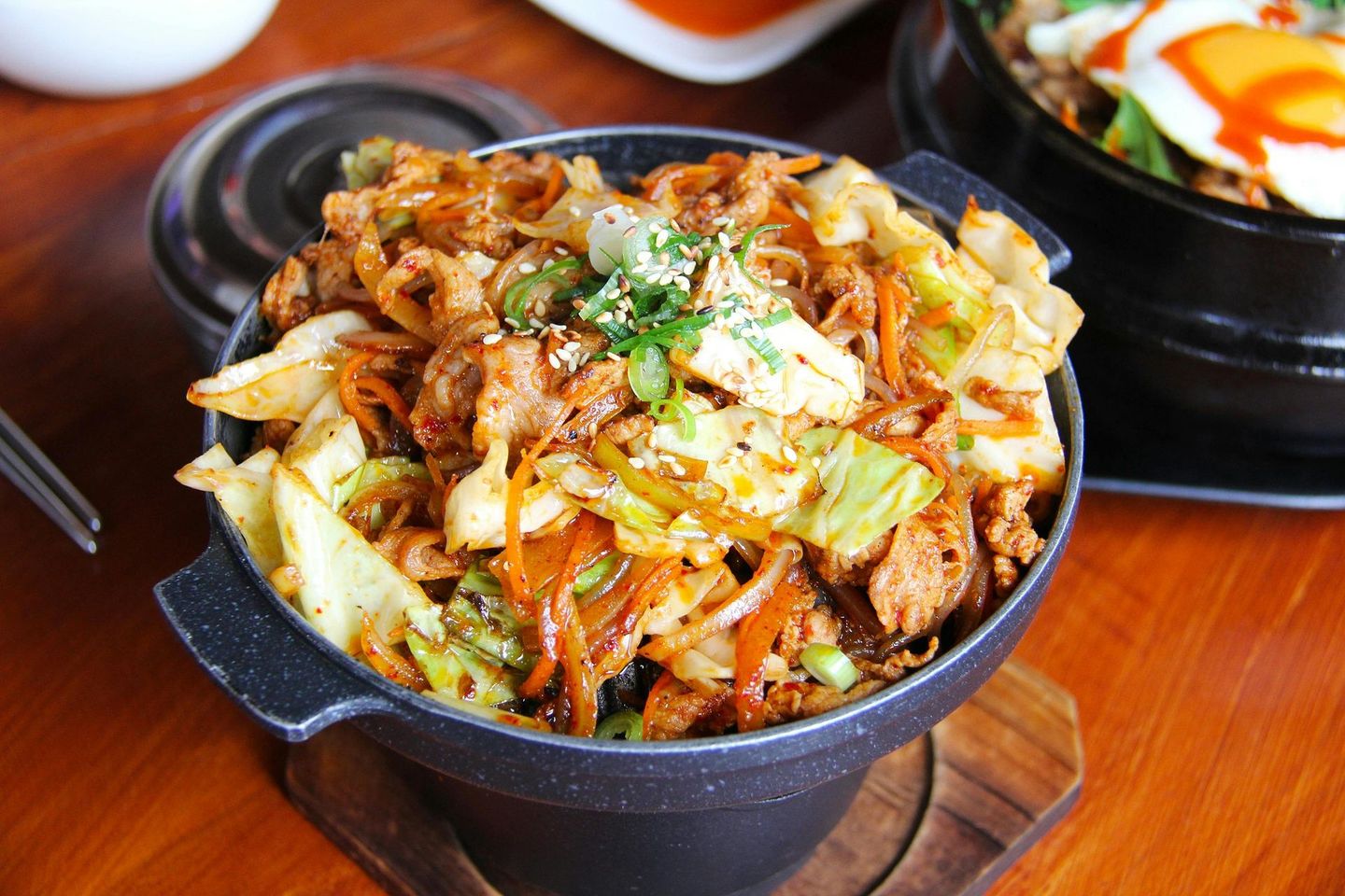 A bowl of food with meat and vegetables on a wooden table.
