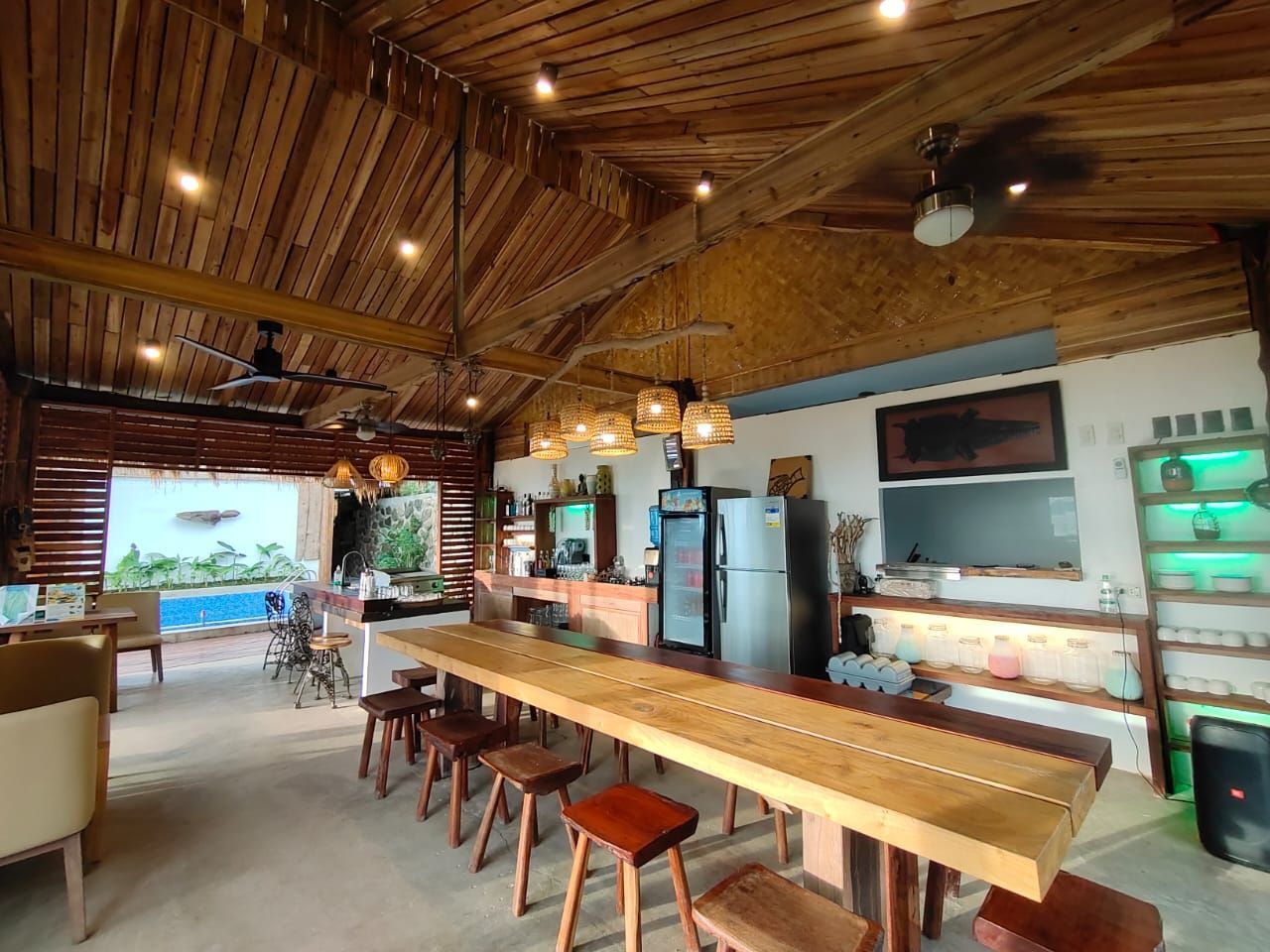 A long wooden table with stools in a room with a ceiling fan.