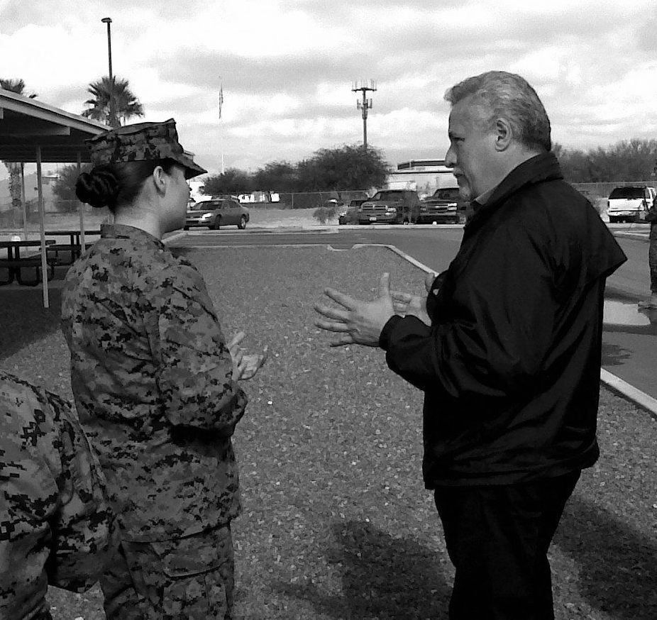 A man and a woman in military uniforms are talking in a parking lot