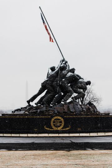 A statue of soldiers raising an american flag in the snow