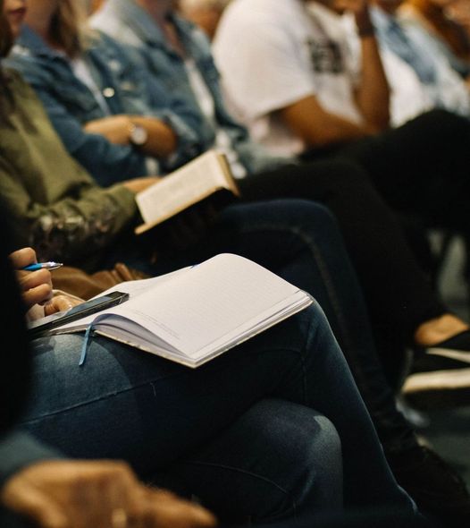 A group of people are sitting in a row reading books and taking notes