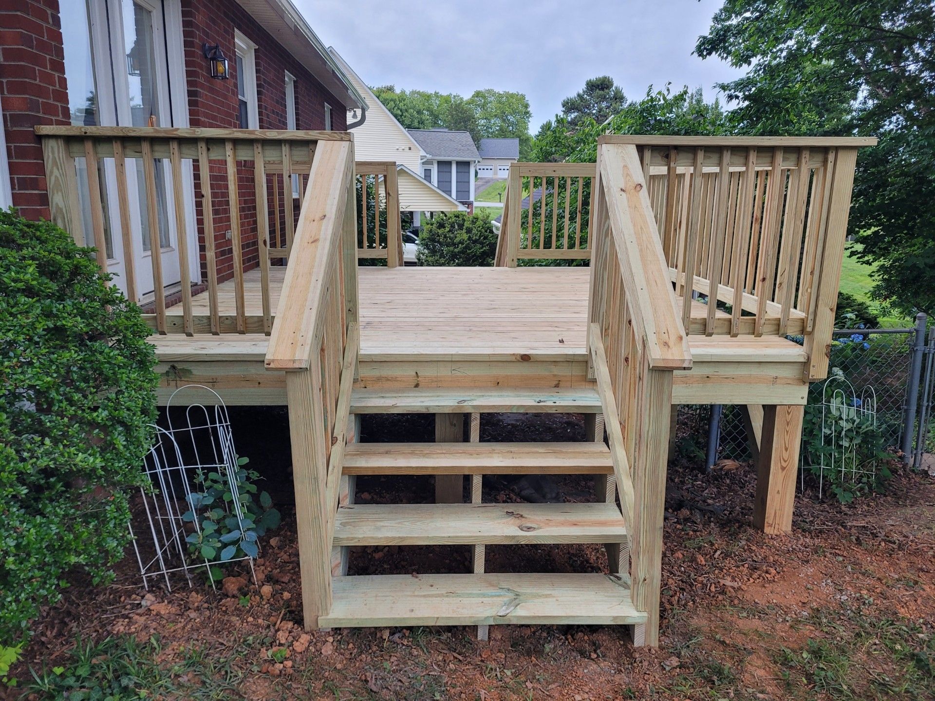 Wooden deck with stairs leading down to yard. Railings on deck and stairs.