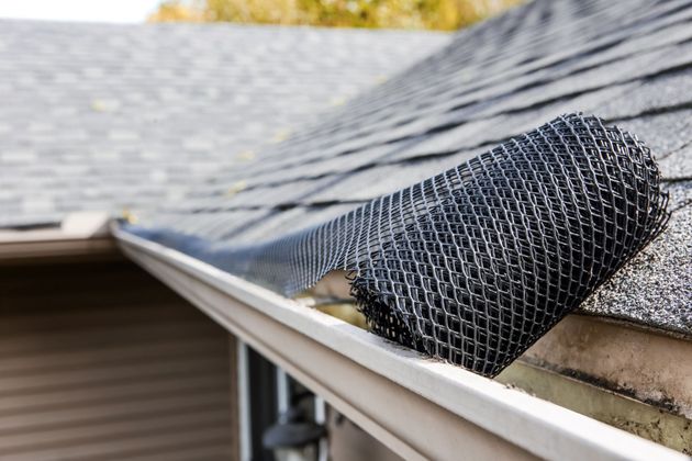 Black gutter guard being installed on a roof, protecting against debris.