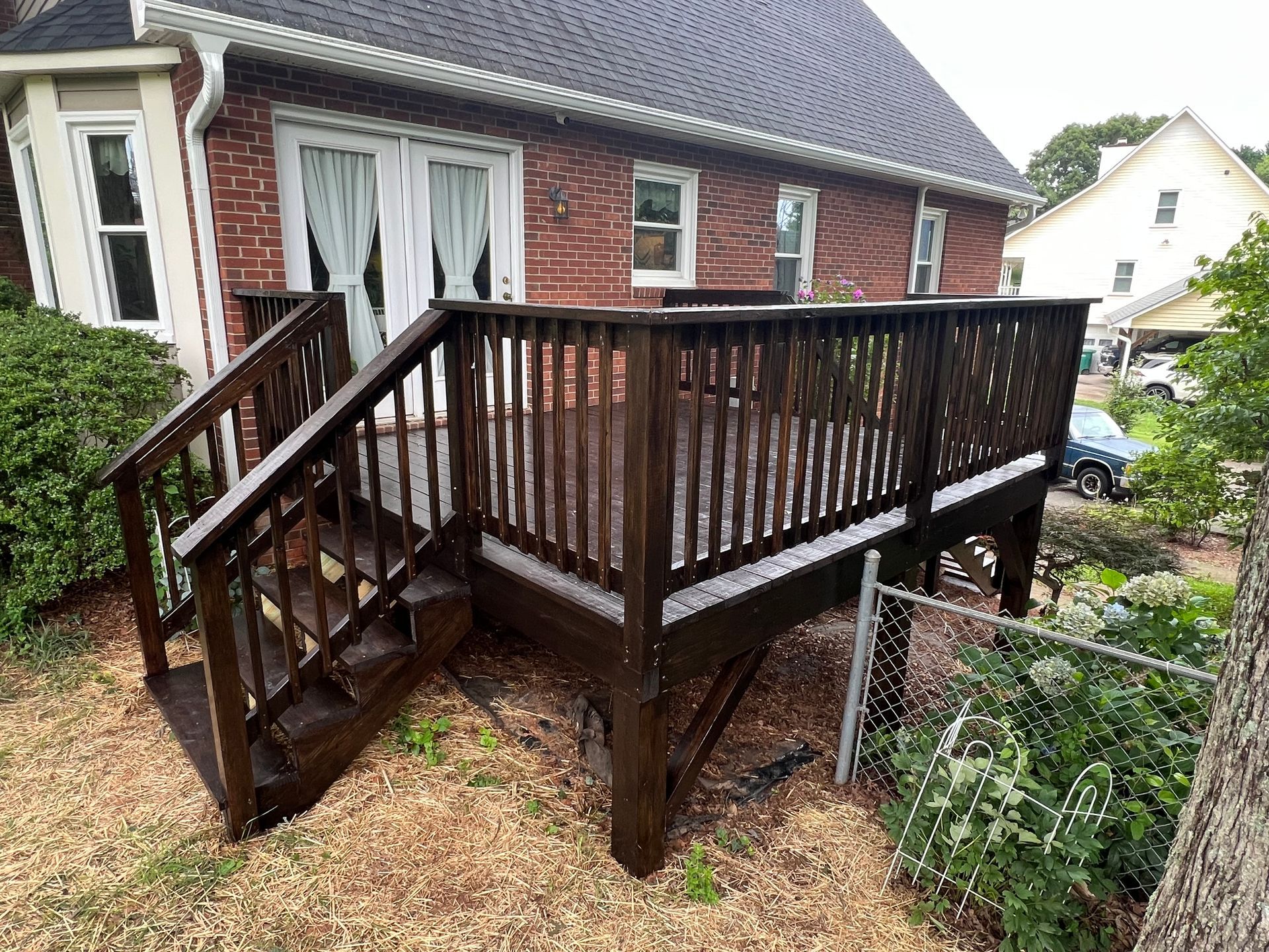 Wooden deck with stairs attached to a red brick house.