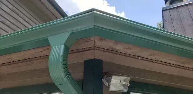 Green gutters on a building corner. A downspout is visible.