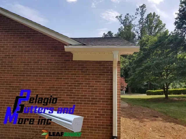 A brick building with white gutters installed by Pelagio Gutters and More. Bright sunny day.