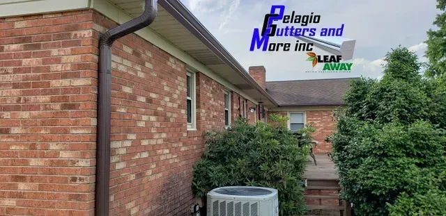 Brown gutters on a brick house with an air conditioning unit and bushes. Company logo.