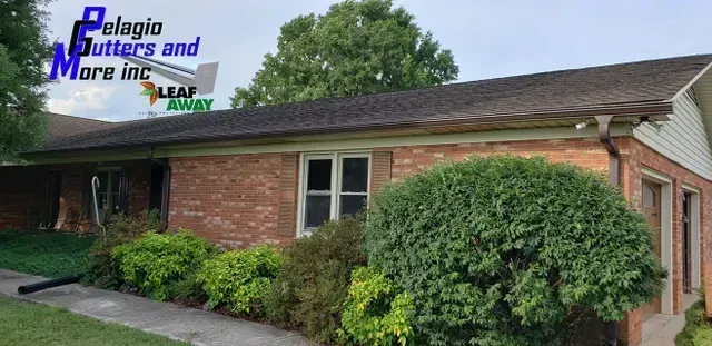 House with brick exterior and green shrubbery, rain gutters by 