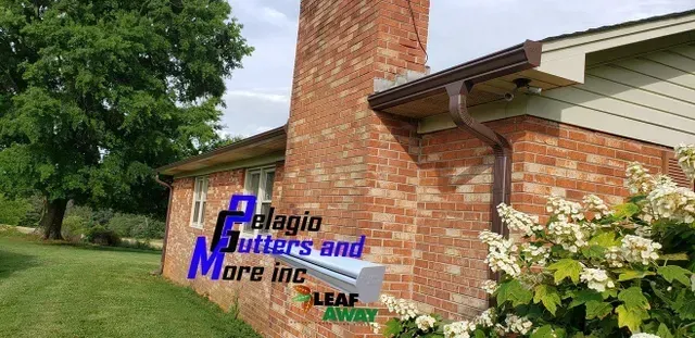Brick chimney and house with brown gutters; Pelagio Gutters and More Inc. sign.