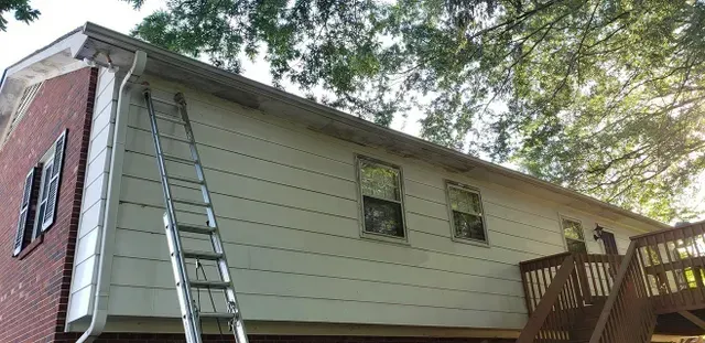 House exterior with a ladder against the wall and a wooden deck.
