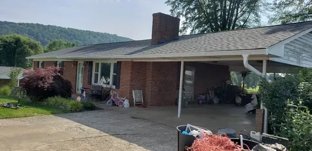 A brick ranch-style house with a carport and a mountain in the background.