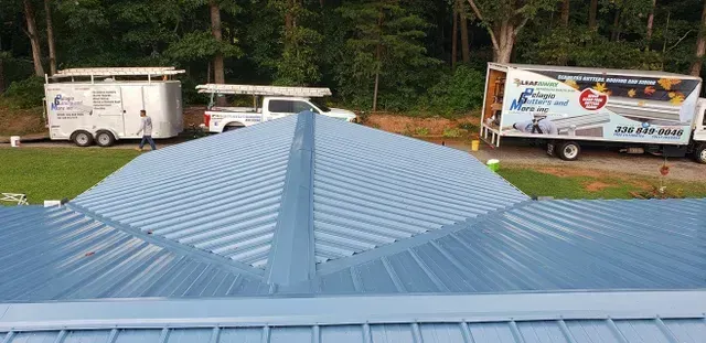 Blue metal roof, with repair trucks parked, forest in the background.