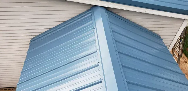 Blue metal roof corner with white trim and siding.