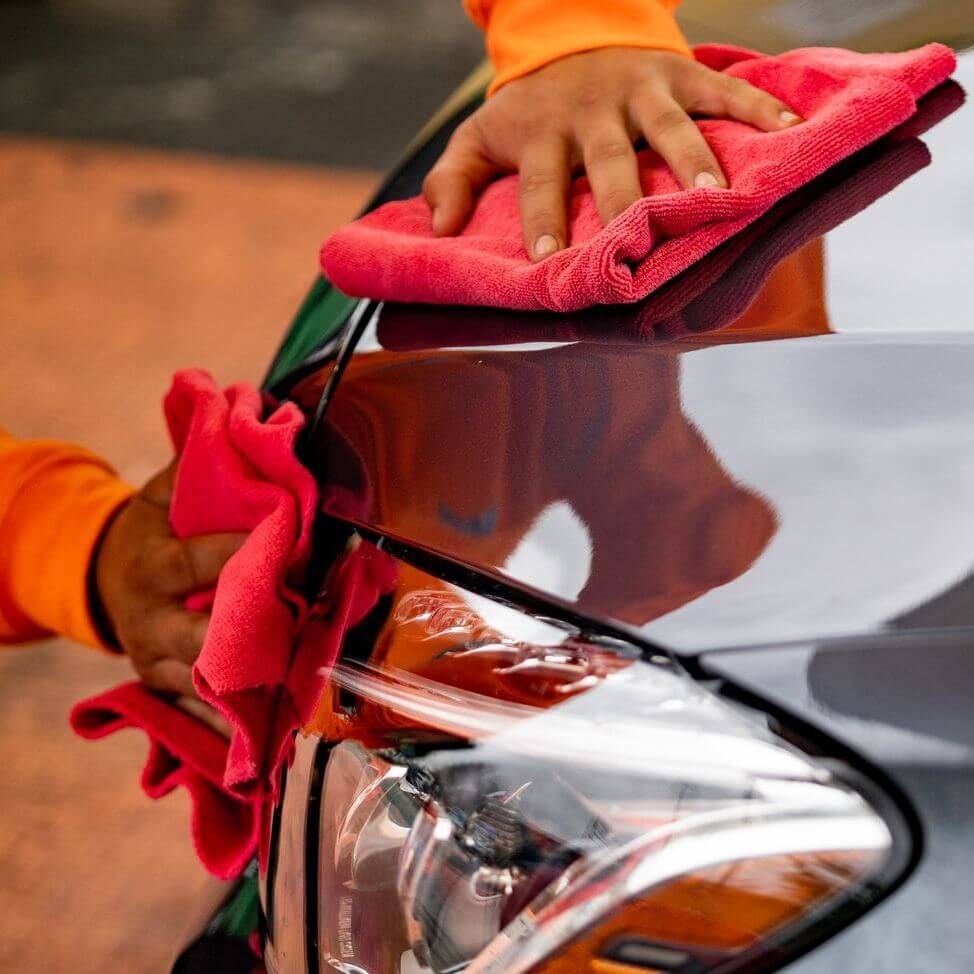 a person is cleaning a car with a red cloth