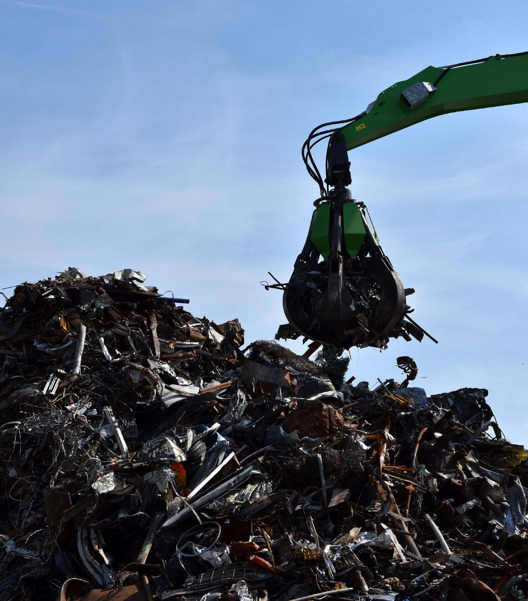 Una gru verde solleva rottami metallici