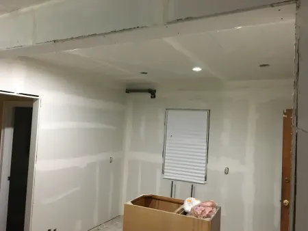 A man wearing a hard hat and safety glasses is working on an air conditioner.