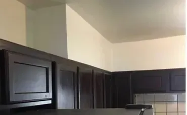 A kitchen with black cabinets , a refrigerator , and a microwave.