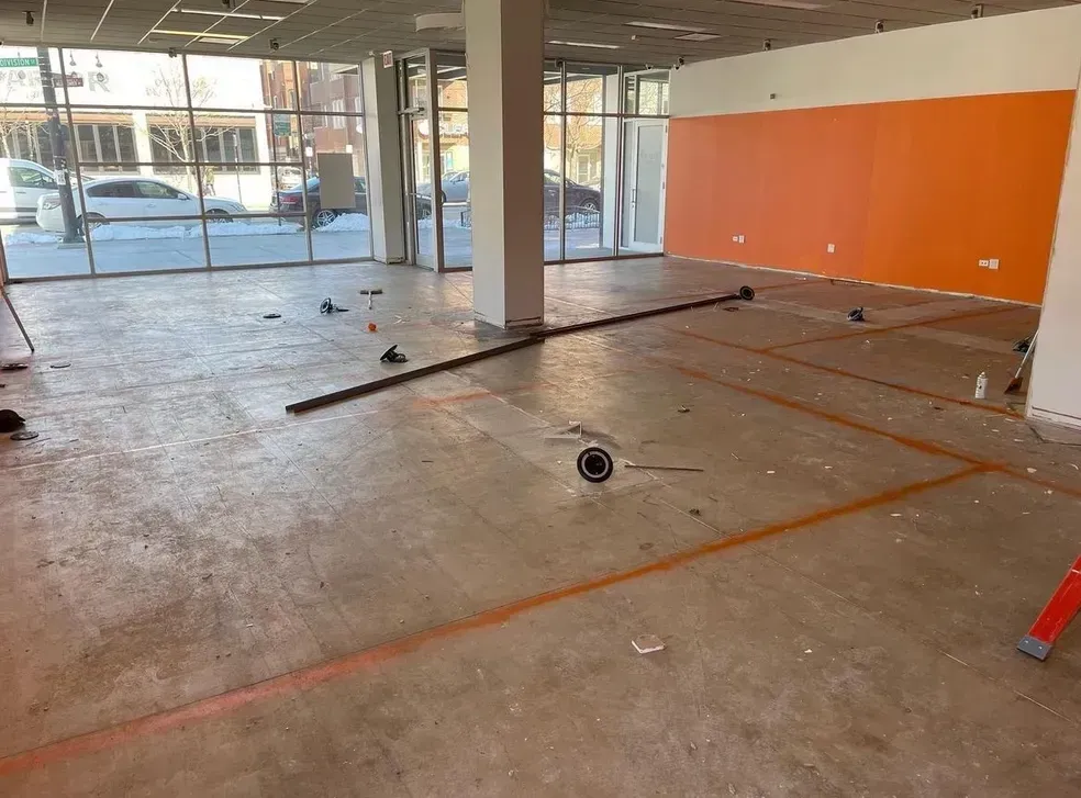 A large empty room with a lot of windows and a vacuum cleaner on the floor.