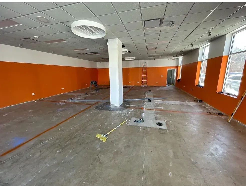 A large empty room with orange walls and a ladder.