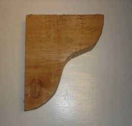 Wooden bracket, tan color, with curved edges.