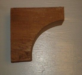Wooden shelf bracket, stained brown, with curved support.