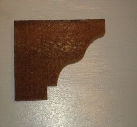 Brown wooden corbel with decorative curves.