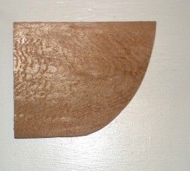 Wooden, quarter-circle shaped piece of wood with textured grain on a white surface.