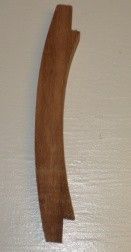 Curved, wooden handle with notched ends, likely from a tool or furniture.