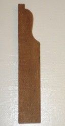 Wooden architectural molding, a decorative element with a curved top and rectangular body.