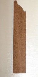 Brown wooden molding piece with curved top, on a light background.
