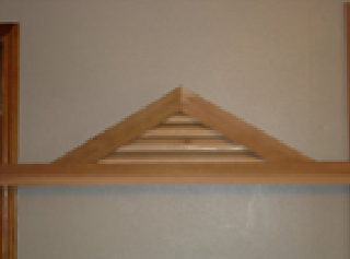 Wooden arched window shutter with horizontal slats on a gray wall.