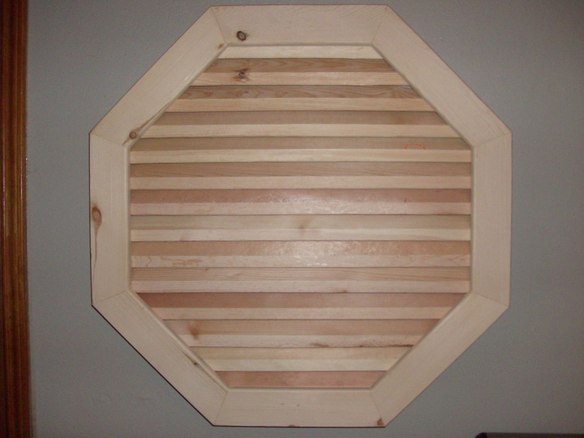 Octagonal wooden frame with horizontal slats on a gray wall.