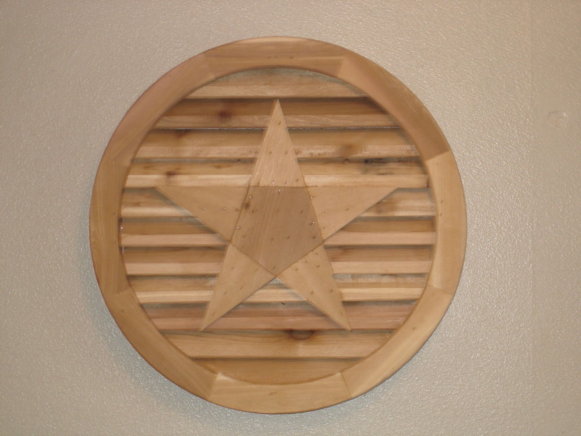 Wooden star within a circular frame on a slatted background, mounted on a wall.