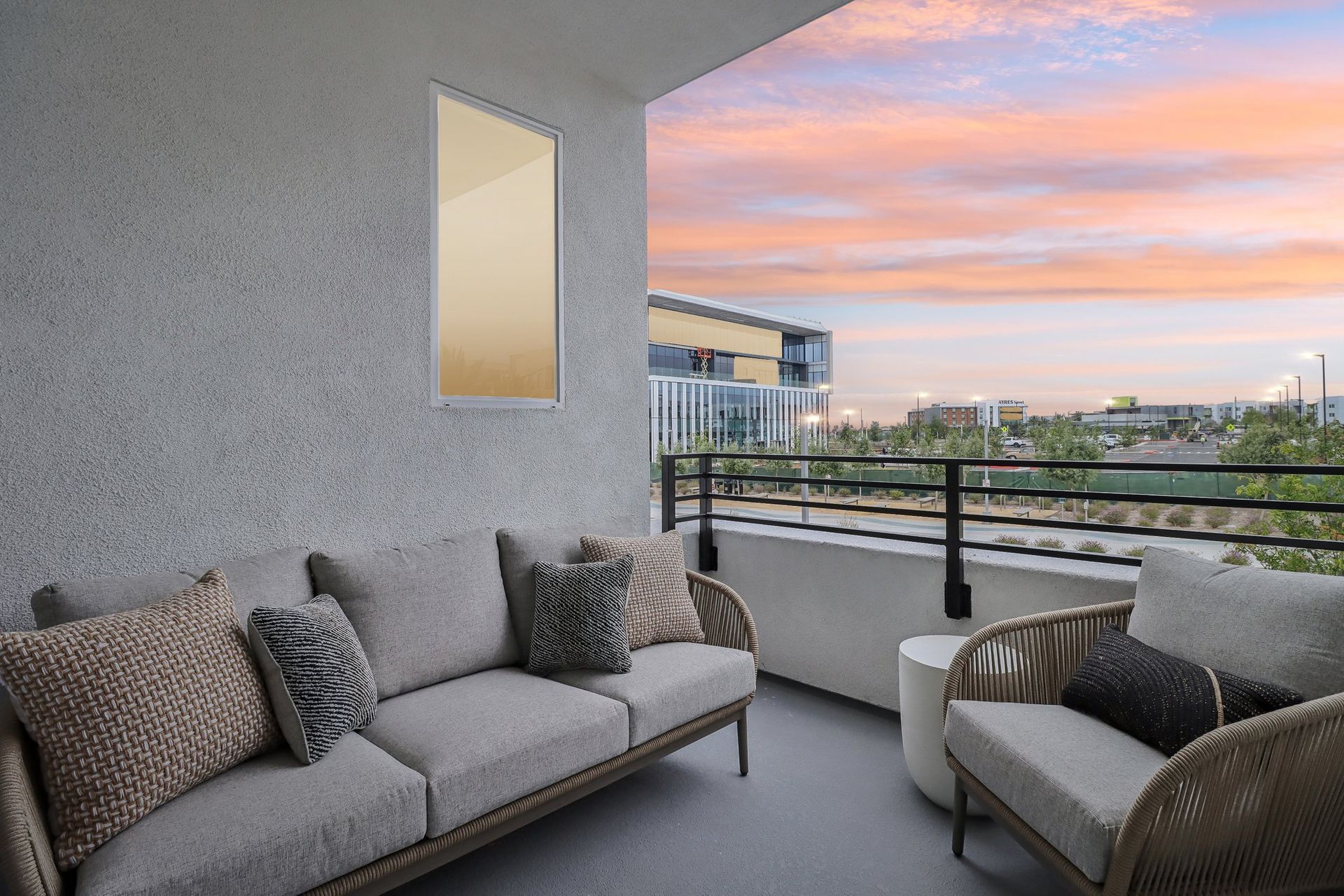 A balcony with a couch and chairs and a view of the city.