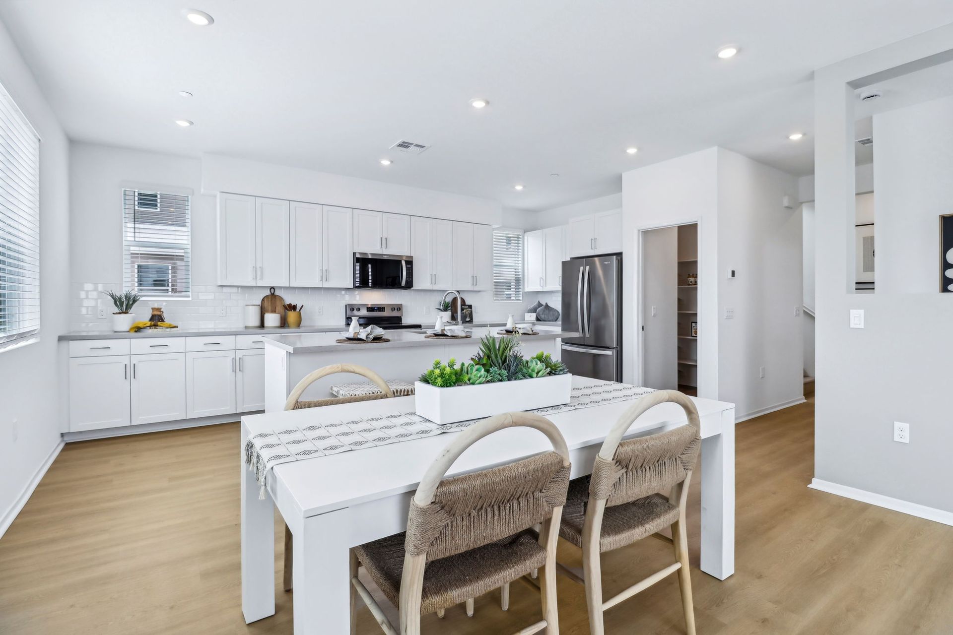 Open-concept kitchen and dining area with white cabinets, island, table, and chairs.