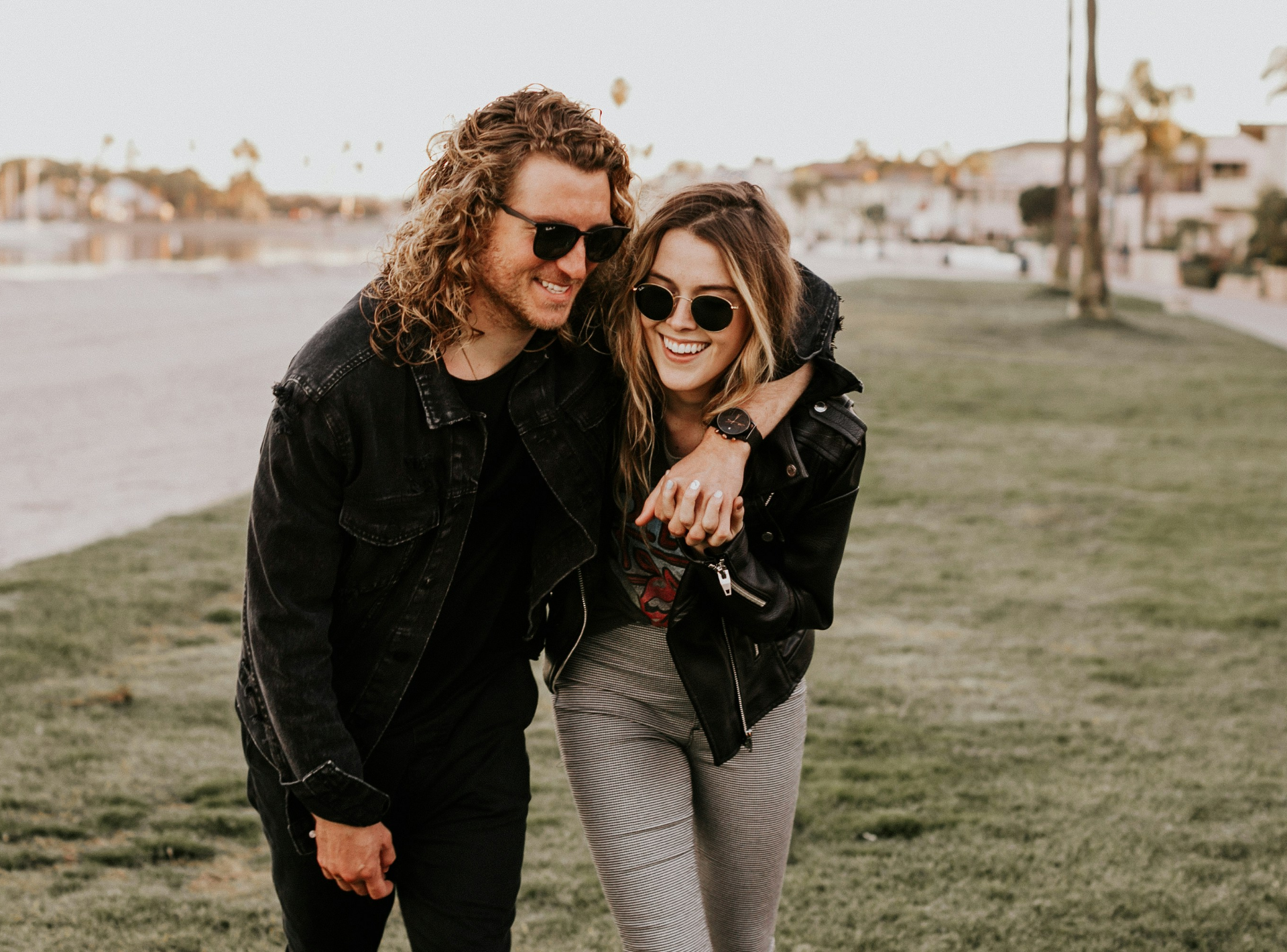 A man and a woman wearing sunglasses are walking in the grass