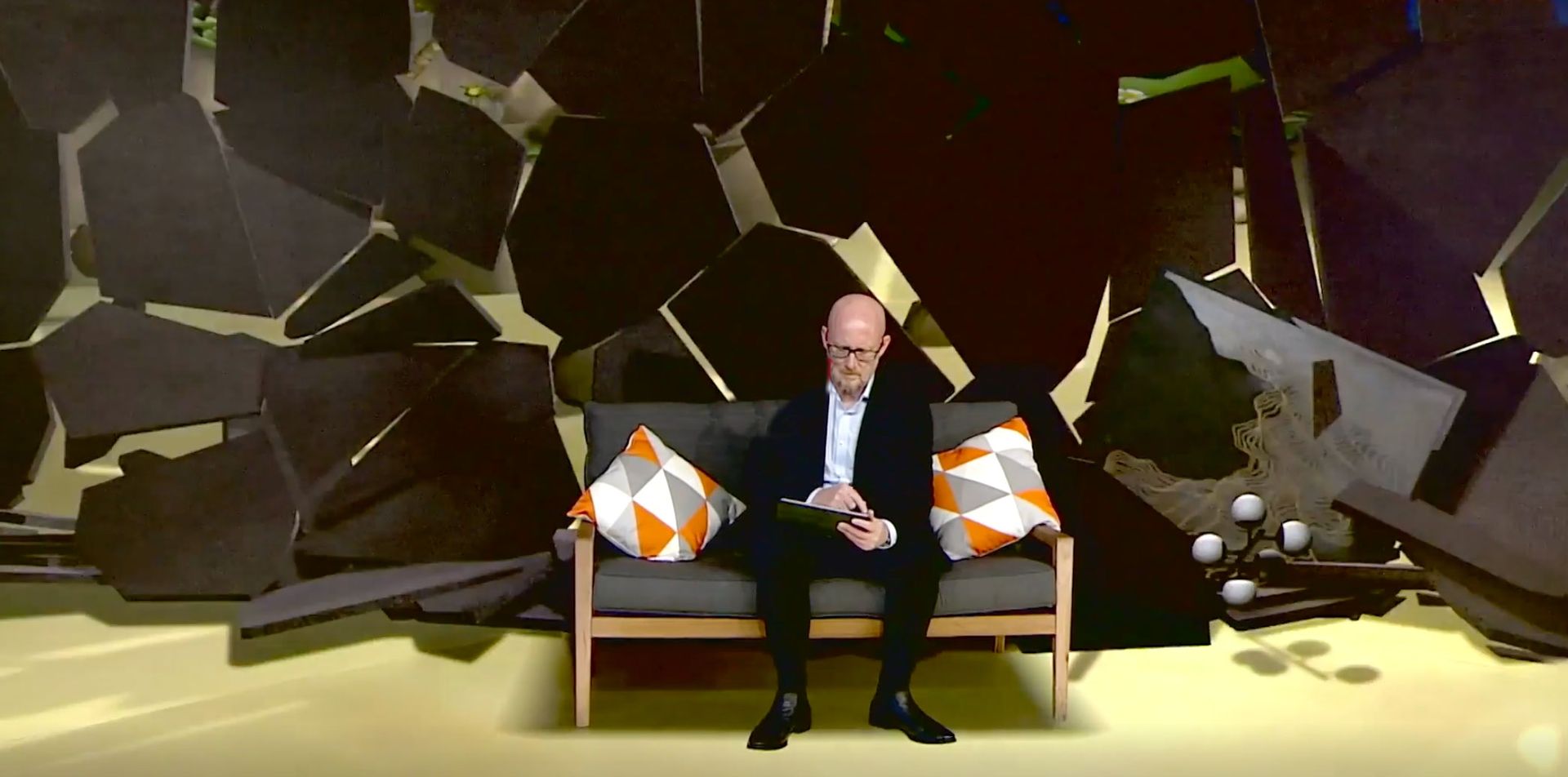 man sat on sofa in front of LED backdrop that breaks away