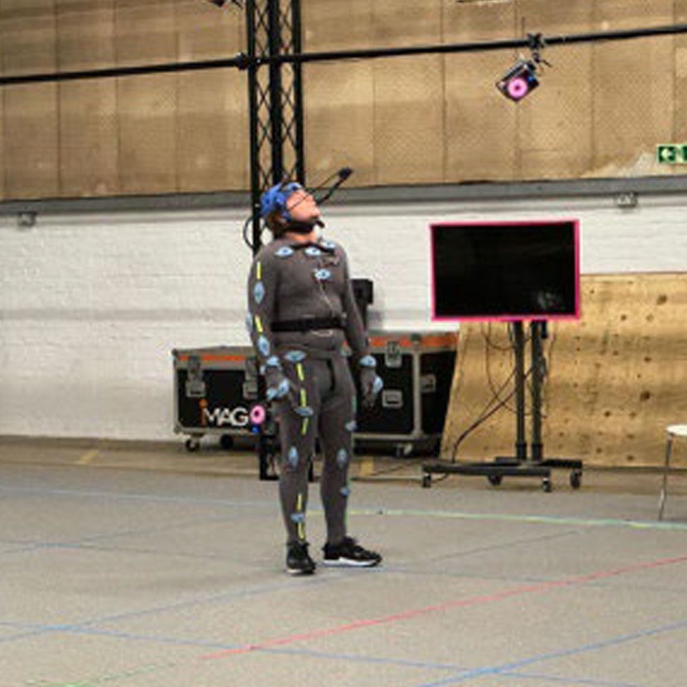 A man in a suit is standing in front of a monitor