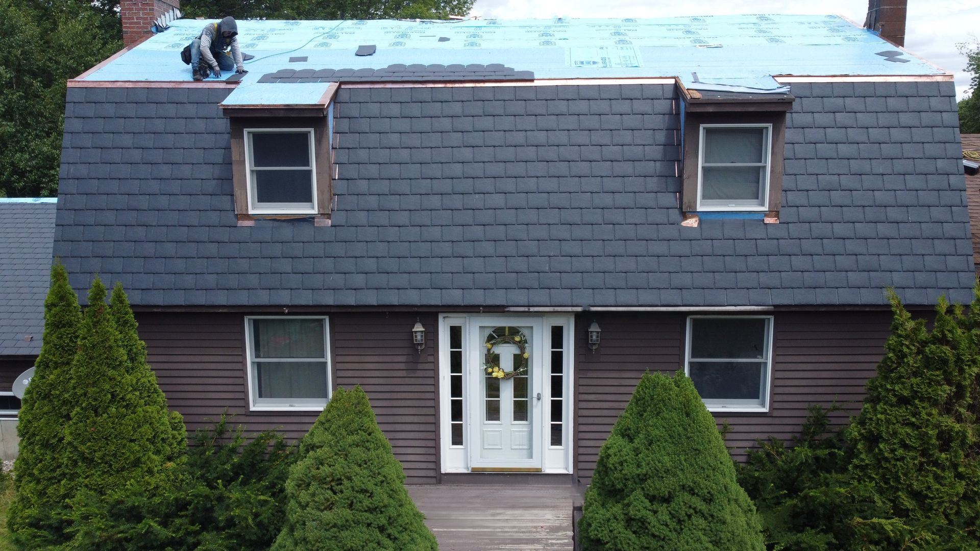 An aerial view of a house with a slate roof being installed.