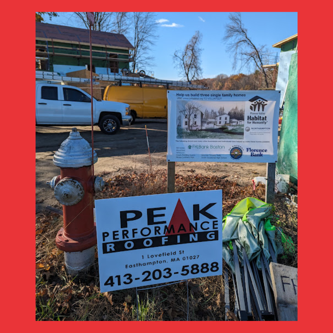 A sign for peak performance roofing is next to a fire hydrant