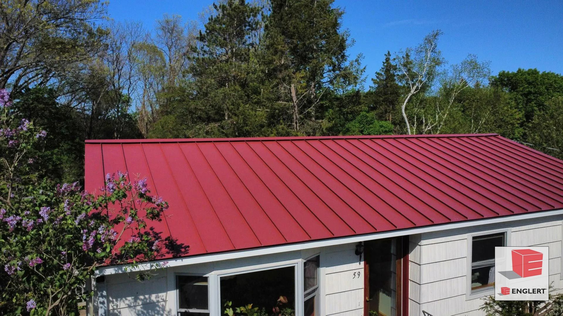 A white house with a red metal roof.