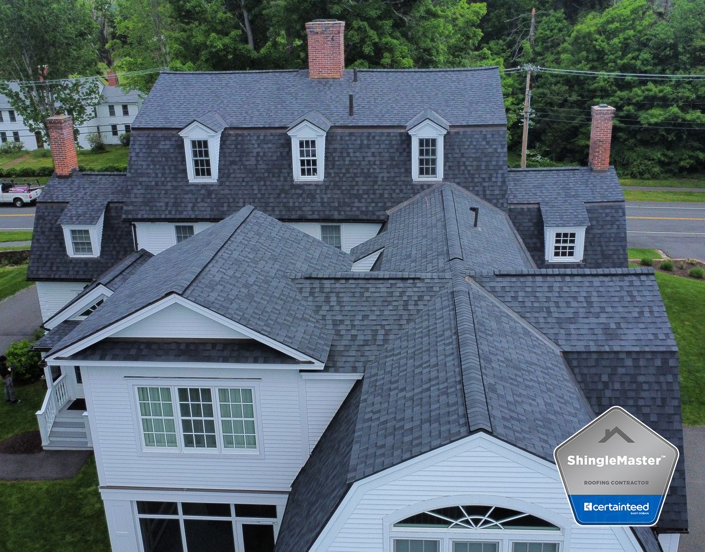 An aerial view of a large house with a shingle roof.