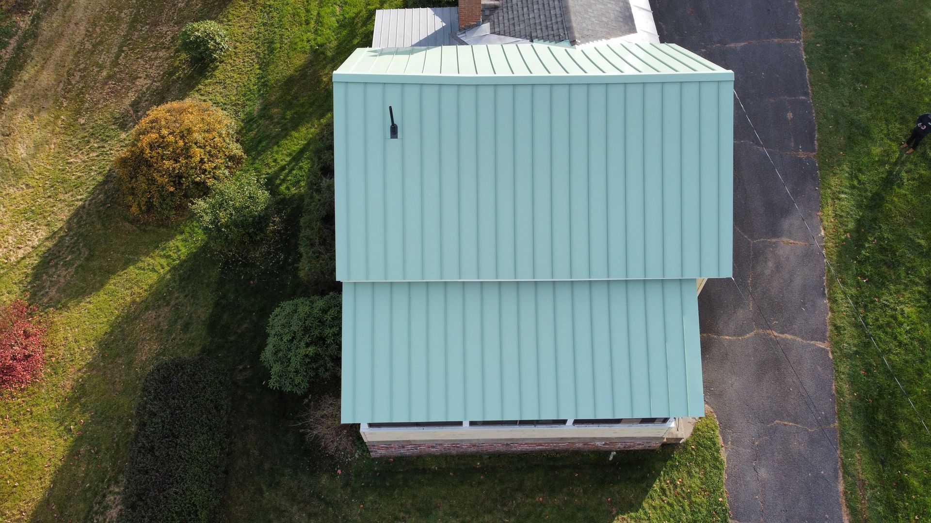 An aerial view of a house with a green roof and a driveway.