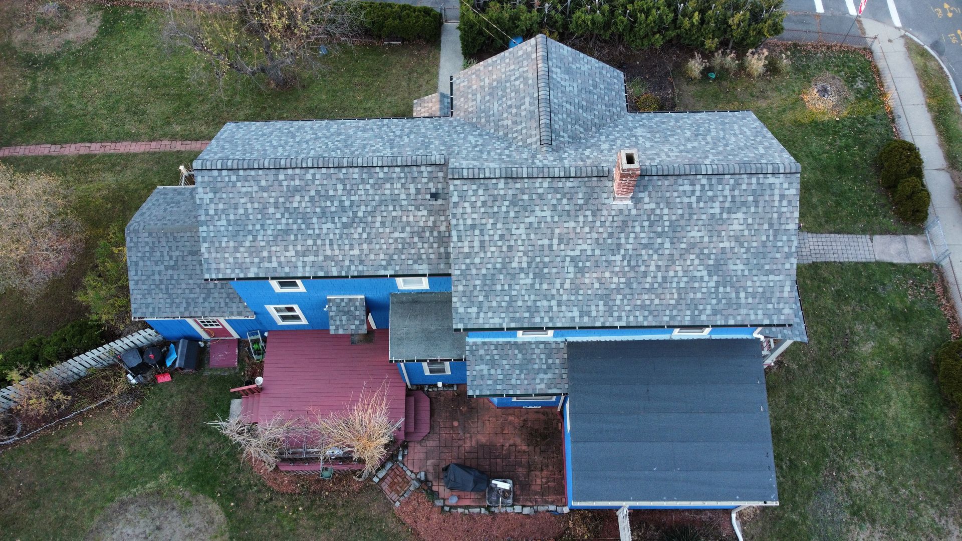 An aerial view of a large blue house with a gray roof.