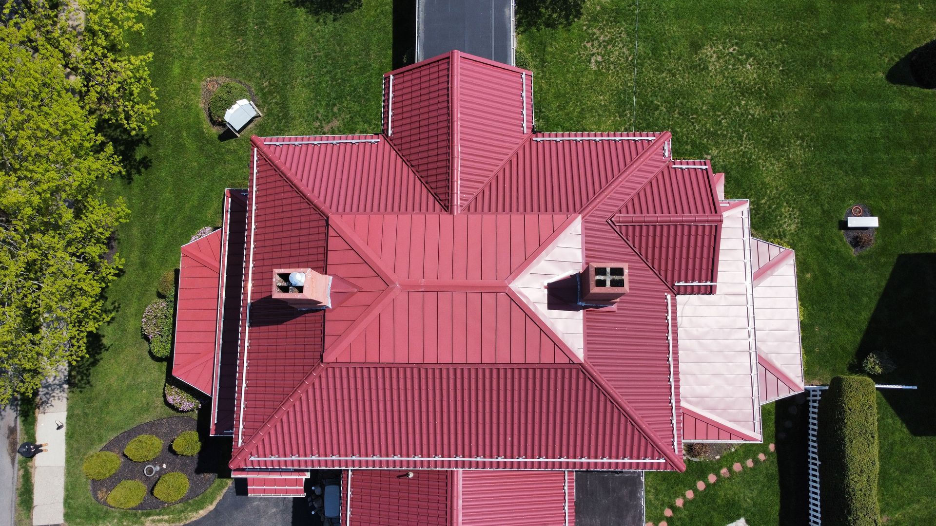 An aerial view of a large house with a red metal roof and chimneys. An aerial view of a large house with a red metal roof and chimneys.