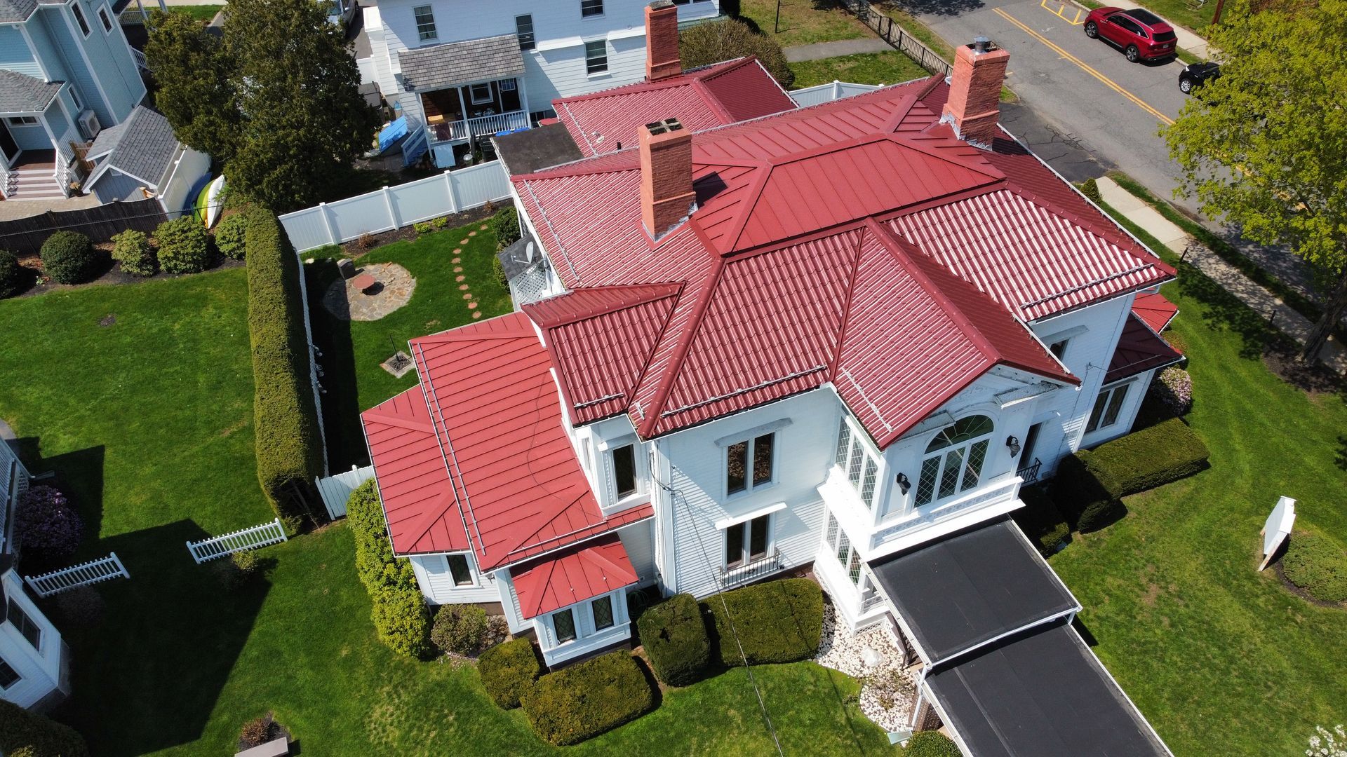 An aerial view of a large white house with a red tiled roof.