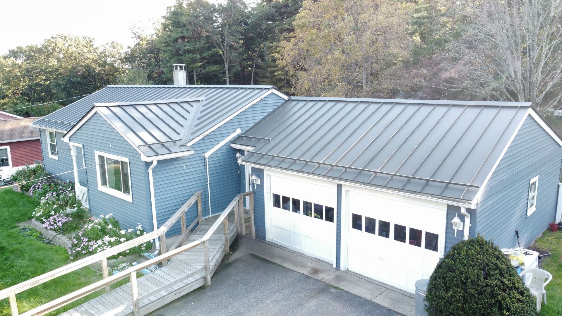 An aerial view of a blue house with a metal roof and a garage.